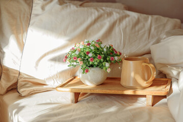 Breakfast in bed with coffee and a potted plant on a wooden tray.