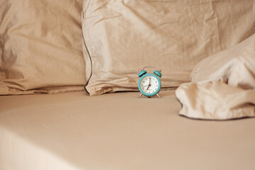 Alarm clock on an unmade bed in the morning light.
