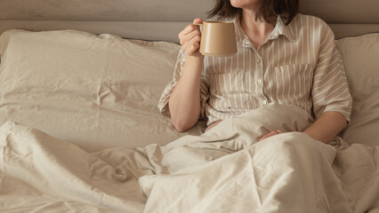 A woman enjoying coffee in a cozy bed.