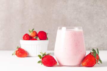 Glass of fresh strawberry milkshake, smoothie and fresh strawberries on white and wooden background. Healthy food and drink concept.