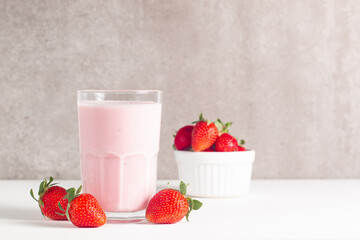 Glass of fresh strawberry milkshake, smoothie and fresh strawberries on white and wooden background. Healthy food and drink concept.