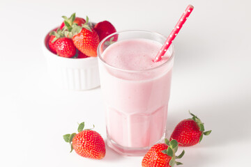 Glass of fresh strawberry milkshake, smoothie and fresh strawberries on white and wooden background. Healthy food and drink concept.
