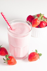 Glass of fresh strawberry milkshake, smoothie and fresh strawberries on white and wooden...