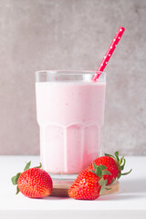 Glass of fresh strawberry milkshake, smoothie and fresh strawberries on white and wooden...