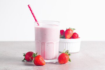 Glass of fresh strawberry milkshake, smoothie and fresh strawberries on white and wooden background. Healthy food and drink concept.