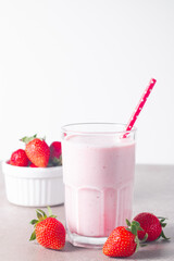 Glass of fresh strawberry milkshake, smoothie and fresh strawberries on white and wooden background. Healthy food and drink concept.