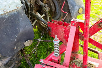 Agricultural machinery mechanisms connected by chains and springs against a backdrop of green...