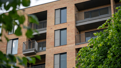 New apartment residential facade with multiple glass balcony unit and green foliage view