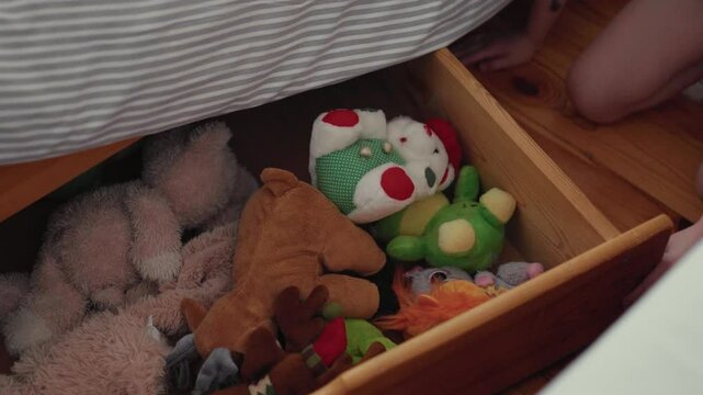 Child puts up her toys away in an under bed storage box.	
