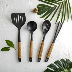 Elegant Black Kitchen Utensils with Wooden Handles on White Background near Tropical Leaves