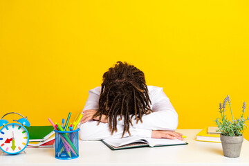 Young student resting over book in a vibrant yellow classroom environment symbolizing education fatigue and focus