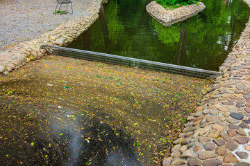 A creek trash trap is a grate used to trap trash in the water of a small stone-paved canal