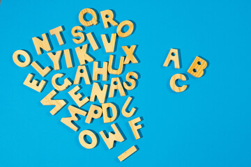 ABC alphabet wooden letters on blue background. Language learning or teaching.