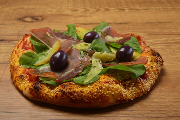 Pizza de rúcula com presunto cru e parmesão. Borda de gergelim