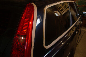 Detail-oriented car polishing in an indoor workshop highlights the rear window trim and taillight...