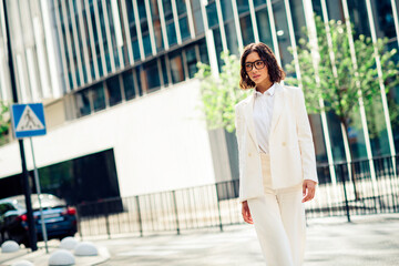 Successful businesswoman walking confidently in modern urban environment, stylishly dressed in a...