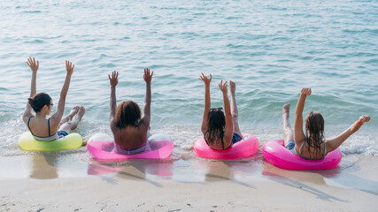 A group of carefree teenagers laughing and playing in the sea with colorful inflatable swim rings, capturing the essence of youthful joy, friendship, and summer fun by the sea.