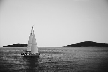 Sailboat gracefully navigating calm waters with distant islands.