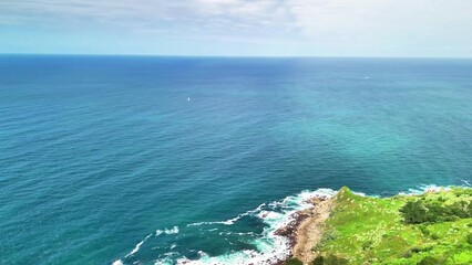 A breathtaking aerial view showcasing stunning coastal cliffs adorned with lush greenery and serene blue ocean waters