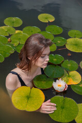 beautiful girl in a lake with nymphs and water lily flowers