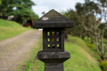 Traditional stone lanterns in a tranquil garden with a backdrop of paths and green trees