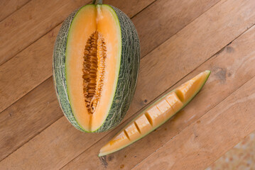 The man use knife split the orange melon on wood plate