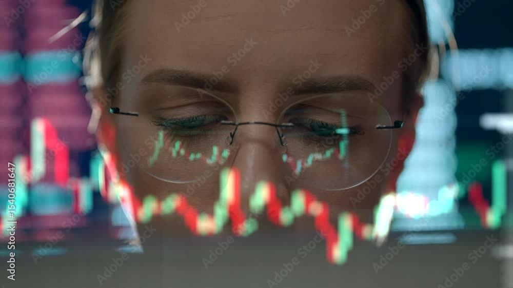 Poster trader wearing glasses is working on laptop computer. screen with stock market charts and bitcoin bt