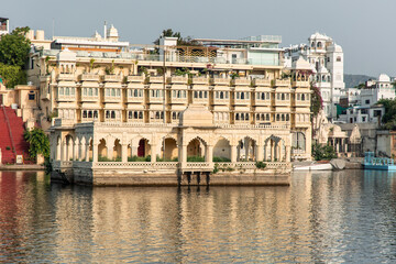 Fototapeta premium Lake Pichola reflecting the facade of the luxurious Taj Lake Palace hotel in Udaipur