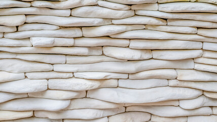 A close-up photograph of a white textured wall with a layered, organic pattern.