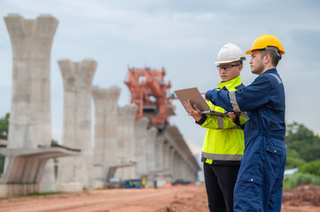 An Asian male engineer works at a motorway bridge construction site,Civil worker inspecting work on crossing construction,Supervisor working at high-speed railway construction site