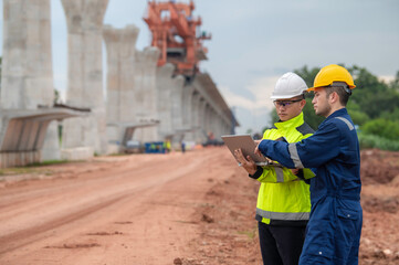 An Asian male engineer works at a motorway bridge construction site,Civil worker inspecting work on...