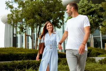 Couple enjoys a leisurely stroll through urban greenery during a bright afternoon in a modern city setting