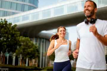 Urban joggers enjoy a sunny morning run in a modern cityscape filled with greenery and bright architecture