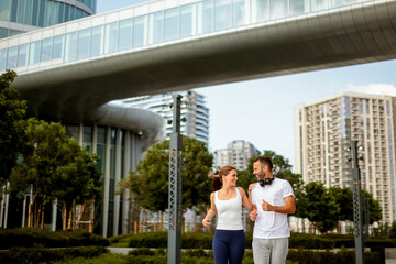 Joyful morning jog at a modern urban park surrounded by sleek skyscrapers and greenery