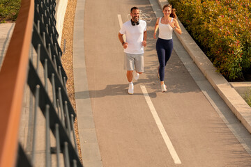 Running together along a peaceful path surrounded by greenery in the bright morning sun