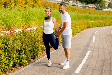 Outdoor stretching session in a vibrant park as a fitness trainer guides a client towards better flexibility and wellness