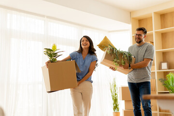 Two friends joyfully moving into their new apartment filled with light and greenery on a bright sunny day
