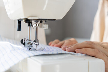 woman sews a light fabric on a sewing machine. making clothes, hobbies. a sewing studio, a clothing designer, a tailor sews on a household sewing machine.