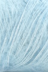 Obraz premium A macro close-up of soft light blue mohair yarn, showing delicate fuzzy fibers and long thin strands running through the textured bundle.