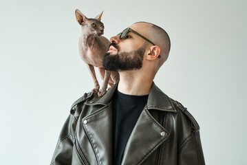 A stylish man with a Sphynx cat on his shoulder, a modern portrait.