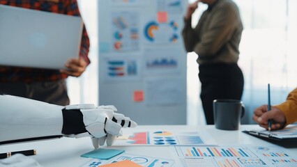 A robot hand reaches toward charts during a business meeting in a modern office, showcasing...