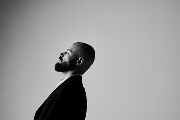 A man with a beard in a suit looks upward in a classic black and white portrait.