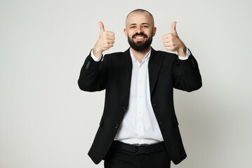 A smiling businessman in a suit gives a thumbs-up, expressing approval and success.