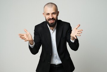 A joyful businessman in a suit gestures with his hands, smiling widely.