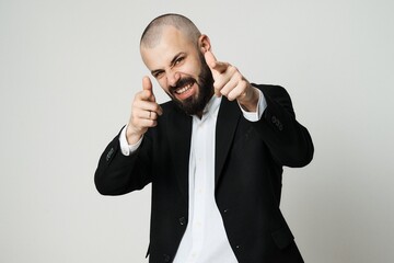 A well-dressed man playfully points at the camera with a focused expression
