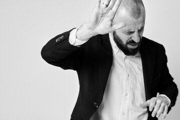 A surprised man in a suit puts his hand up in reaction to something, in monochrome.
