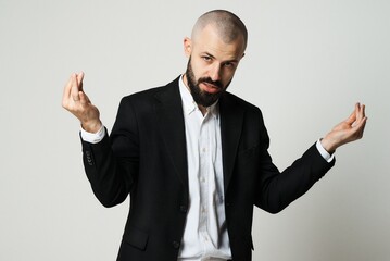 A stylish man in a suit makes expressive hand gestures against a plain background.