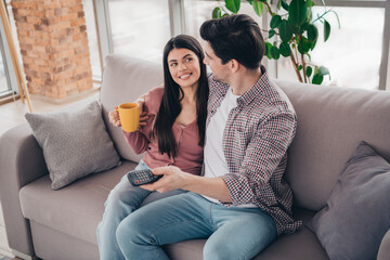 Obraz premium Young couple enjoying together time on the sofa, sharing a warm and happy moment at home during a bright and relaxed day.