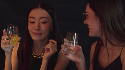 Smiling beautiful customer talking with friend at luxurious bar serving cocktail vodka with slice orange by bartender in moment capture scene enjoyment social community atmosphere at club. Vinosity.