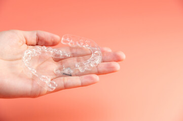 female patient holds two transparent dental aligners in her palms. concept of equal healthy teeth